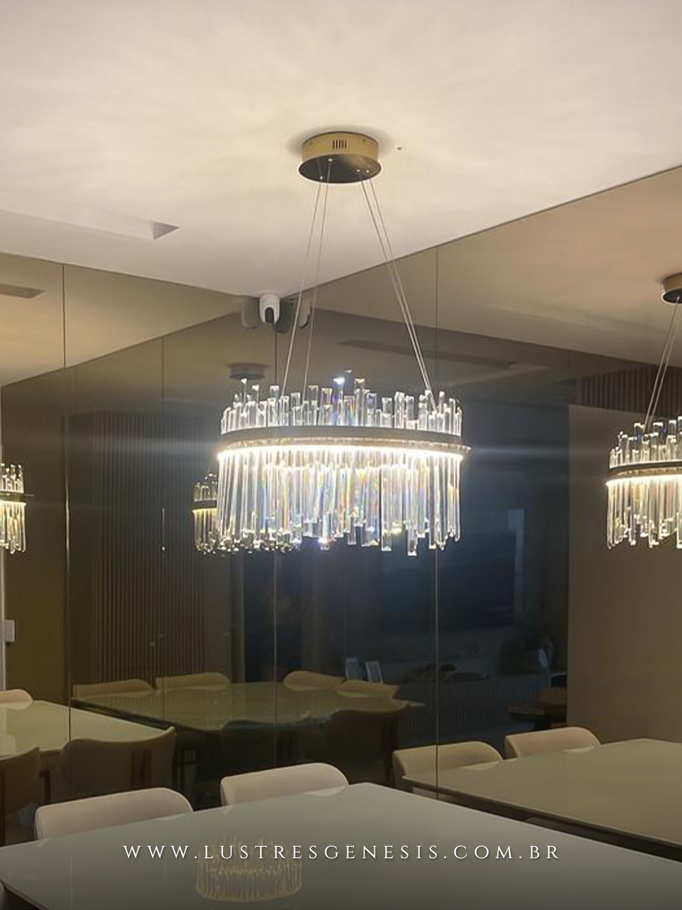 Lustre pendente de cristal modelo Roma New instalado em sala de jantar moderna, refletido em espelho, com mesa e cadeiras ao redor.